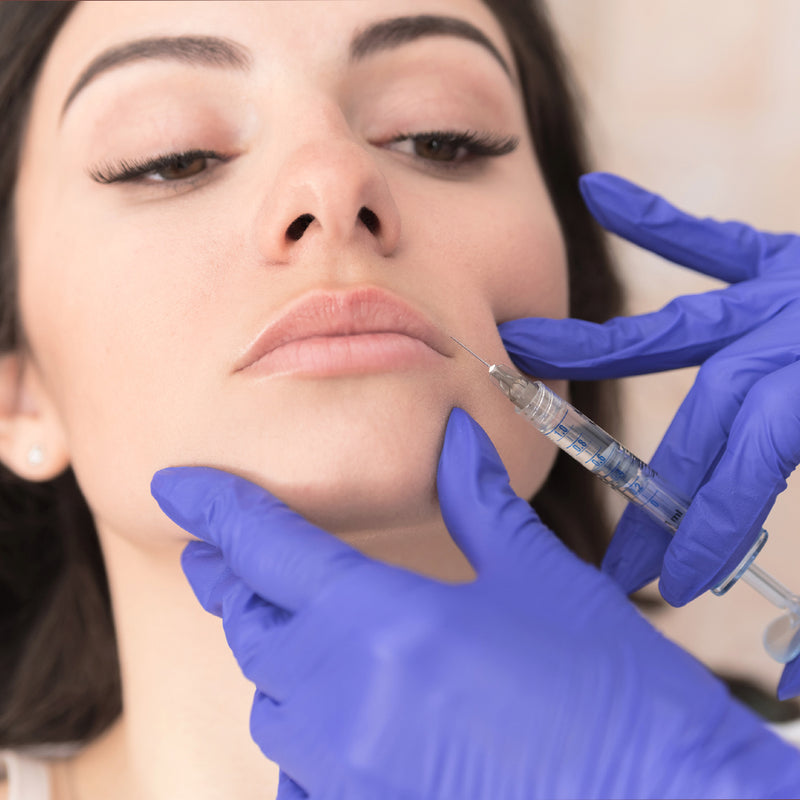 Medical provider preparing to inject Juvederm hyaluronic dermal gel filler into lips. for lip augmentation.